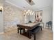 Game room with a unique pool table with bench seating, modern light fixture, and a decorative brick accent wall at 6313 Bordeaux Cir, Sanford, FL 32771