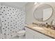 Cozy bathroom showcasing granite countertop, round mirror and shower with patterned curtain at 652 Rochester St, Oviedo, FL 32765
