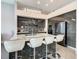 Modern kitchen island has white leather bar stools and features a marble countertop with a drop-down chandelier at 748 Desert Mountain Ct, Reunion, FL 34747