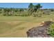 Scenic golf course with green fairways and mature trees, offering a picturesque view from an elevated rock outcrop at 7652 Whisper Way # 301, Reunion, FL 34747