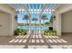 Relaxing view of the pool through a pergola, creating a serene oasis with tropical palm trees and clear blue skies at 7652 Whisper Way # 301, Reunion, FL 34747