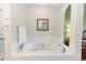 Bright bathroom features a white soaking tub with tile surround and decorative beach themed artwork at 8100 Poinciana Blvd # 2109, Orlando, FL 32821