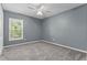 Neutral bedroom with carpet flooring, ceiling fan, and a bright window providing natural light, offering a relaxing space at 817 Benton Lake S Dr, Deland, FL 32724