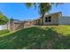 An expansive backyard features a brick retaining wall, partial view of the screened-in pool, and a covered patio area at 902 Wingate Trl, Port Orange, FL 32128