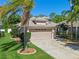 Attractive front exterior view of home with a two-car garage, palm trees, and well-maintained landscaping at 902 Wingate Trl, Port Orange, FL 32128