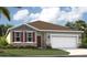 Charming single-Gathering home with a well-manicured lawn, two car garage, and red shutters at 9161 Harris Hawk Dr, Leesburg, FL 34788