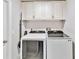 Bright laundry room with modern washer and dryer units and overhead cabinets at 9338 Palm Tree Dr, Windermere, FL 34786