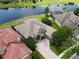Aerial view of a beige home featuring a tile roof, brick driveway, well-maintained landscaping and a serene lake at 1027 Algare Loop, Windermere, FL 34786