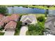 Aerial view of a beige home featuring a tile roof, brick driveway, and serene lake views at 1027 Algare Loop, Windermere, FL 34786