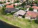 Aerial view of a residential area with houses featuring tiled roofs, well-manicured lawns, and a beautiful lake at 1027 Algare Loop, Windermere, FL 34786