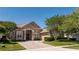 Charming beige single-story home with a tile roof, a brick driveway and mature landscaping at 1027 Algare Loop, Windermere, FL 34786