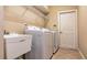 Functional laundry room with washer, dryer, utility sink, and overhead wire shelving for organized storage at 1027 Algare Loop, Windermere, FL 34786