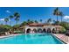 Resort style pool with a Spanish style club house framed with palm trees and deck chairs at 1027 Algare Loop, Windermere, FL 34786
