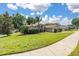 Beautifully landscaped front yard featuring a lush green lawn and mature trees surrounding a charming single-story home at 1034 Featherstone Cir, Ocoee, FL 34761