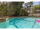 Sparkling in-ground pool with waterfall feature surrounded by lush greenery and screened enclosure at 1034 Featherstone Cir, Ocoee, FL 34761