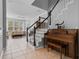 Open-concept living room with large windows, tile flooring, and staircase with decorative piano at 109 Grinnell Pl, Celebration, FL 34747
