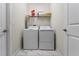 The laundry room features white tile floors, washer, dryer, shelving, and white walls at 1571 Palmero Way, Davenport, FL 33896