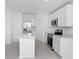 Modern white kitchen featuring stainless steel appliances, an island, and tile floors at 1649 Teagan Ln, Winter Haven, FL 33884