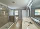 Bathroom features double sinks, white cabinets, framed mirrors, tiled floors, bathtub, and tiled shower with glass door at 191 Chickasaw Berry Rd, Ocoee, FL 34761