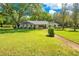 Quaint single-story home with a large tree, mature plantings and walkway leading to the front door at 20 Stone Gate S, Longwood, FL 32779