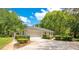 Attached garage with mature plantings, a wide driveway, and convenient access to the property at 20 Stone Gate S, Longwood, FL 32779
