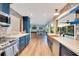 Open-concept kitchen with blue cabinets, stainless steel appliances, stone countertops, and views of the game room and backyard at 20 Stone Gate S, Longwood, FL 32779