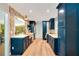 Galley kitchen with stylish blue cabinets, stone backsplash, stainless steel appliances, wood floors, and a pass-through to the dining area at 20 Stone Gate S, Longwood, FL 32779