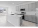 Well-lit kitchen with stainless steel appliances, gray cabinets, a spacious island, and tiled floors at 2030 Firethorn Loop, Haines City, FL 33844