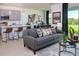 Open living space with a gray sofa, modern decor, an adjacent kitchen, and a view of the backyard at 2030 Firethorn Loop, Haines City, FL 33844