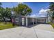 Charming gray home featuring a spacious driveway, well-kept lawn, and patriotic American flag waving in the breeze at 30 Sunset Cir, Lake Alfred, FL 33850