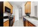 Functional kitchen featuring tile floors, wood cabinets and modern black appliances at 3314 Robert Trent Jones Dr # 308, Orlando, FL 32835