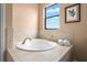 Relaxing bathroom showcases a large soaking tub, framed window, and neutral tile surround at 36813 Barrington Dr, Eustis, FL 32736