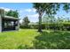 Expansive backyard features lush green lawn, mature trees, and a screened lanai, perfect for outdoor living and entertaining at 3714 Marigot Way, Clermont, FL 34711