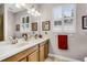 Bright bathroom featuring double sinks, vanity, a large mirror, and plantation shutters on the window at 3714 Marigot Way, Clermont, FL 34711