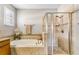 Well-lit bathroom with a soaking tub, tiled shower, and white plantation shutters at 3714 Marigot Way, Clermont, FL 34711