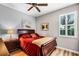 Cozy bedroom with a queen-size bed, wood floors, a ceiling fan, and natural light from the window at 3714 Marigot Way, Clermont, FL 34711