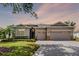 Charming single-story home with a three-car garage, stone accents, and manicured landscaping at dusk at 3714 Marigot Way, Clermont, FL 34711