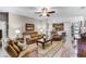 Open-concept living room with tan leather furniture, ceiling fan, and a view of the kitchen at 3714 Marigot Way, Clermont, FL 34711