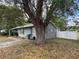 Side view of the home, showing the stucco exterior, mature trees, and a partial view of the fenced backyard at 3845 Sw 148Th Pl, Ocala, FL 34473