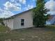 Exterior shot showcasing a tan house in need of repairs, a small window and tree at 4526 Oakton Dr, Orlando, FL 32818