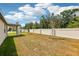 Spacious backyard with a view of the rear of the house and a tall white fence at 4701 Jasmine Cir, Leesburg, FL 34748