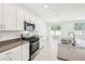 Bright kitchen features stainless appliances, large island with sink, and white cabinetry at 4701 Jasmine Cir, Leesburg, FL 34748
