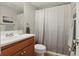 A bathroom with a wooden sink vanity, toilet, white walls, and a shower with a curtain at 4870 Conway Rd # 106, Orlando, FL 32812