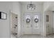 Bright foyer featuring double doors with decorative glass, a modern light fixture, and wood-look floors at 521 Sanctuary Blvd, Winter Haven, FL 33881