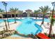 Large community pool with palm trees, lounge chairs, and a fun water slide on a sunny day at 5416 Solterra Cir, Davenport, FL 33837