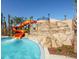 Poolside waterslide with water feature, lush landscaping, and a tanning ledge at 5416 Solterra Cir, Davenport, FL 33837