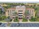 Aerial view of the condo complex showcasing its architecture, balconies, palm trees and lush landscaping at 7651 Whisper Way # 104, Reunion, FL 34747