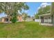 Spacious backyard with a manicured lawn, mature trees, and an enclosed patio area at 7718 Cafaro Dr, Orlando, FL 32818