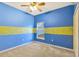 Vibrant bedroom with blue walls and yellow accents, a window, and a ceiling fan at 7718 Cafaro Dr, Orlando, FL 32818