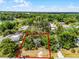 An aerial view of a lot surrounded by lush trees, marked with a red outline on a bright day at 7807 Napoleon St, Orlando, FL 32825